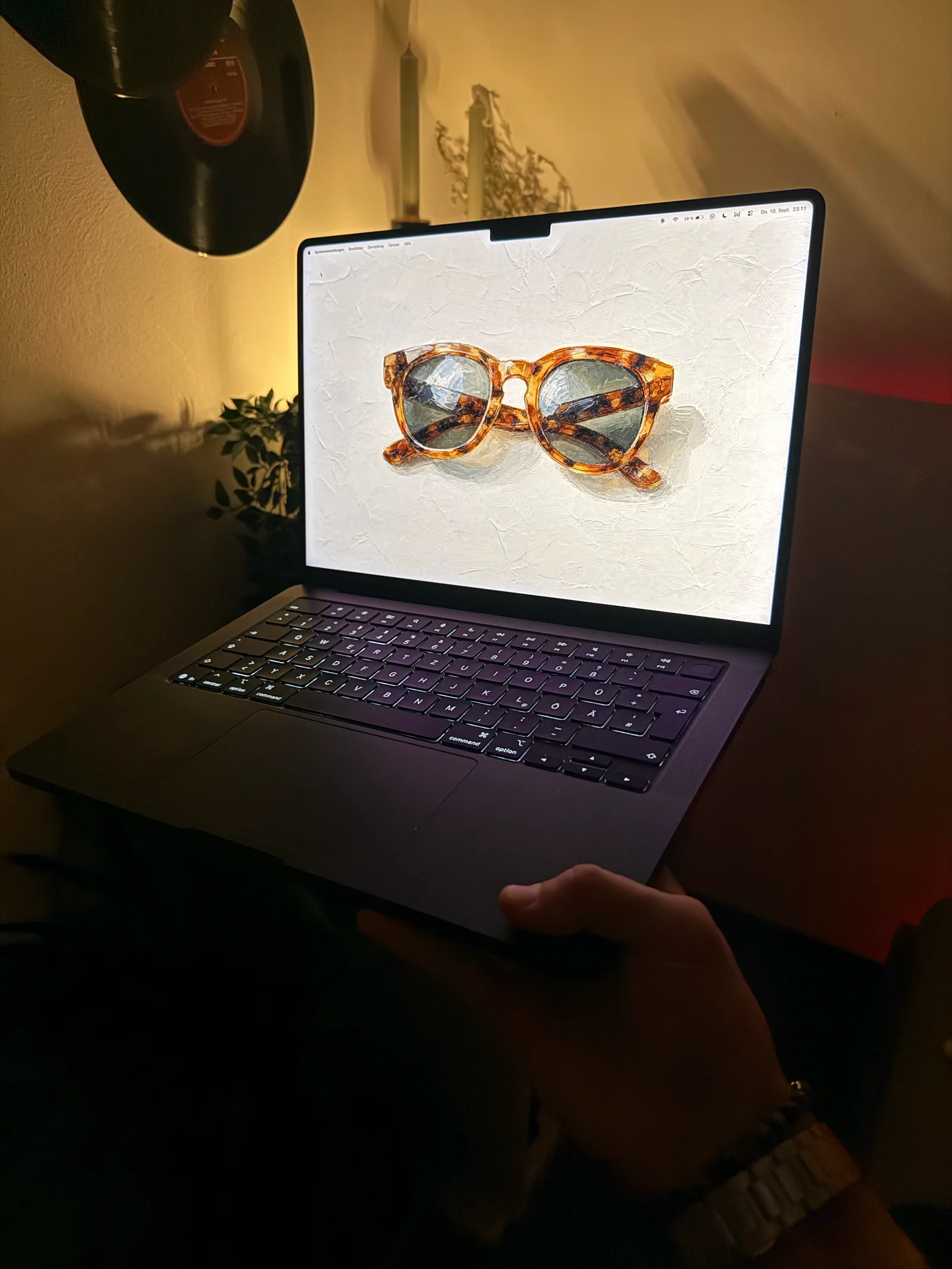 Aufgeklapptes MacBook vor einer Schallplatte an der Wand, auf dem Bildschirm die gefleckte Hornbrille.